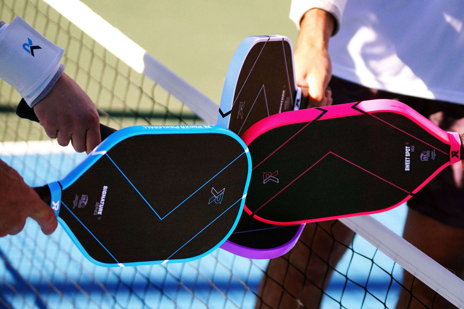 Pickleball players touch together their ProXR pickleball paddles during a game